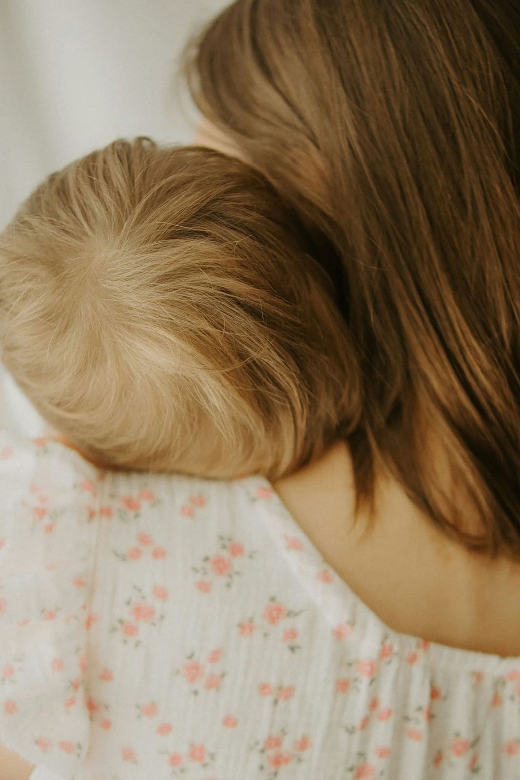 Mutter hält Baby an der Schulter, von hinten